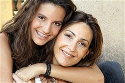 two girls hugging and smiling, one has braces